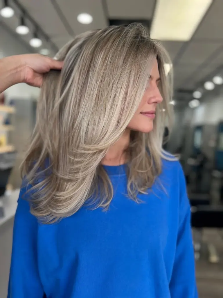 Ash blonde hair in a long layered cut with soft movement