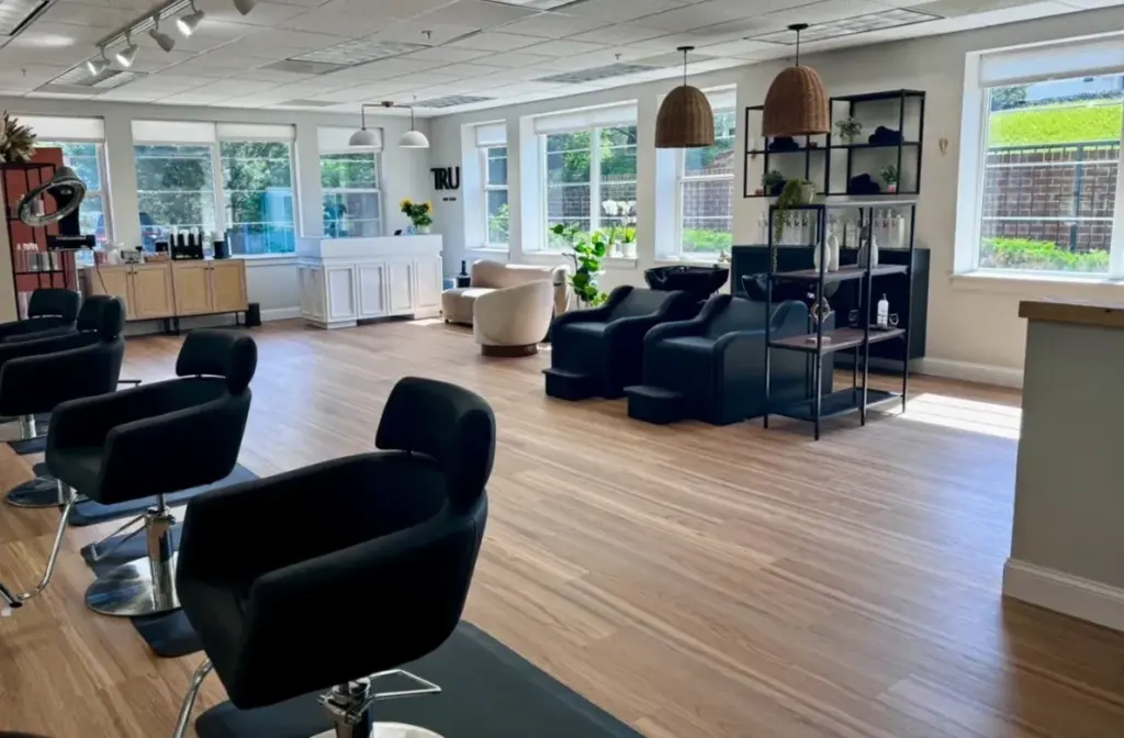 Bright TRU Salon interior in Ashburn with styling chairs, pendant lights and wood floors