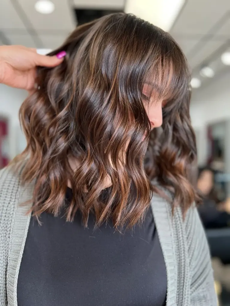 Chocolate-brown hair with warm caramel balayage and curtain bangs