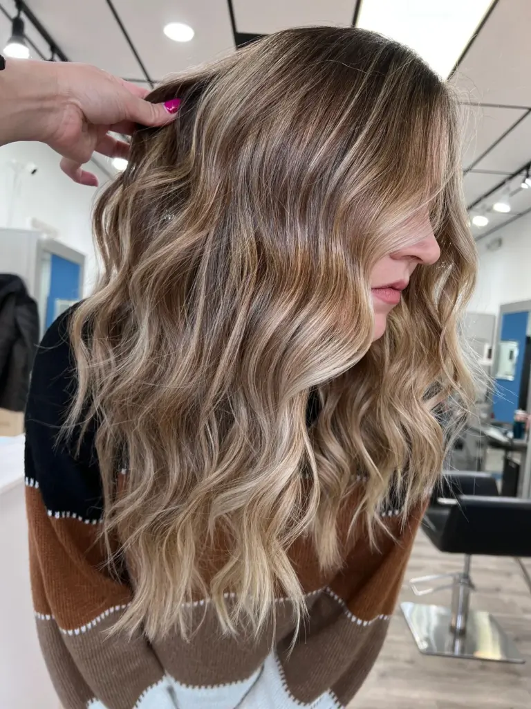 Golden blonde balayage blended through a brunette base in soft waves