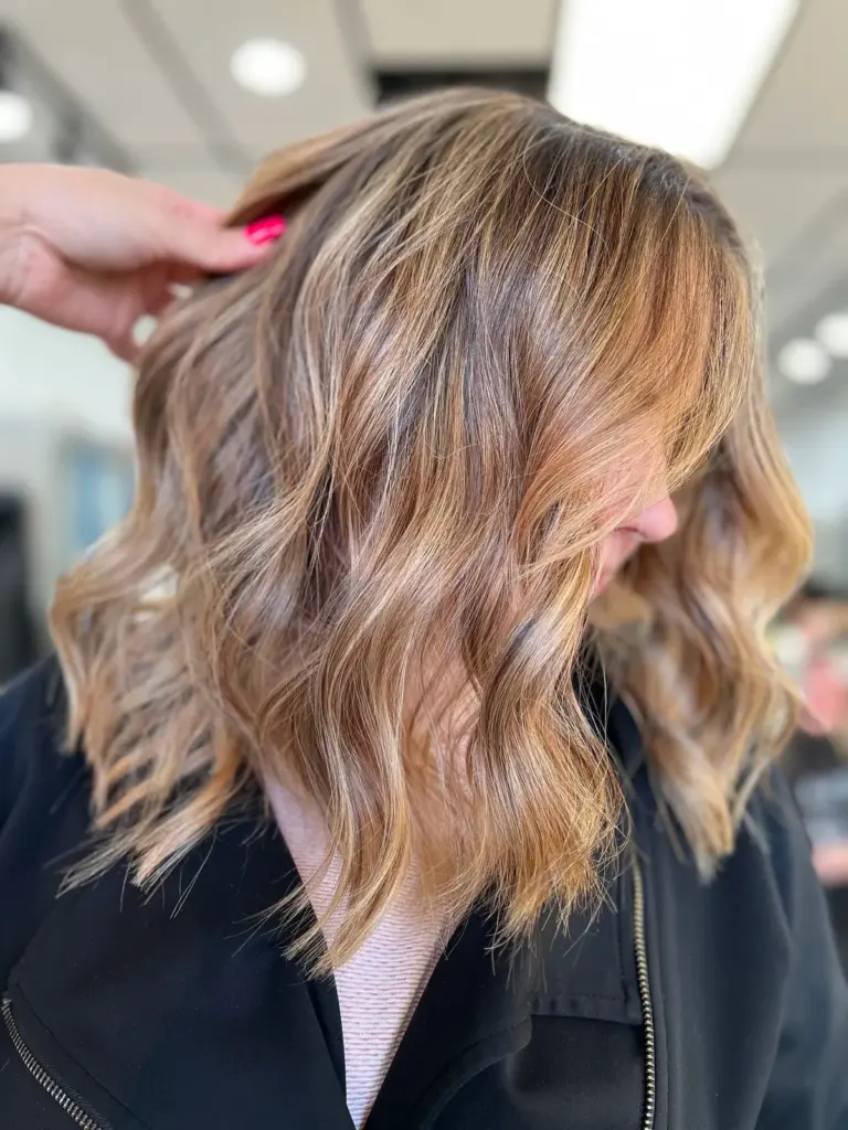 Honey balayage in shoulder-length, softly curled hair